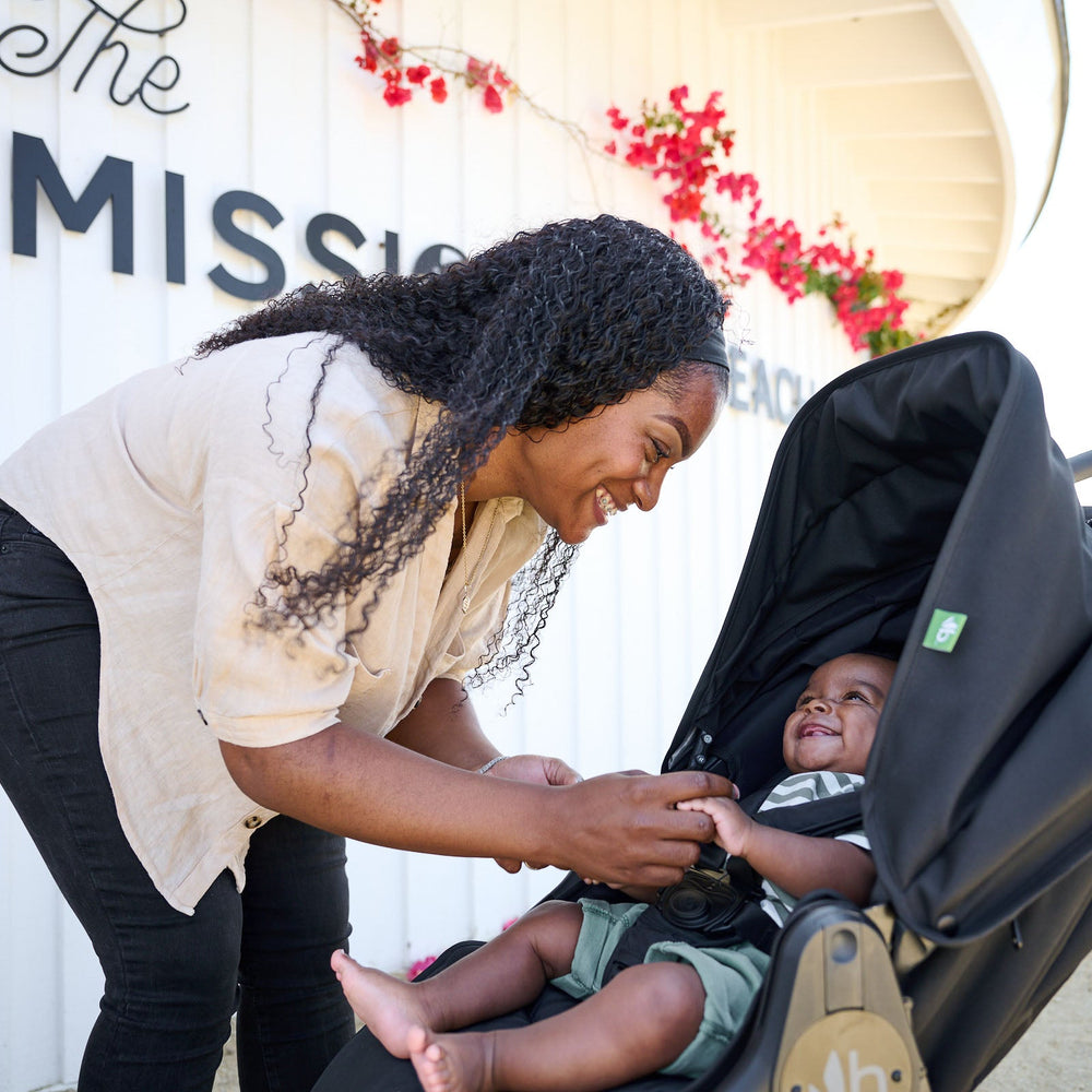 
                      
                        Mother leaning towards stroller seat with smiling baby sitting in bumbleride indie all terrain stroller in black - New Collection 2022 - Global
                      
                    