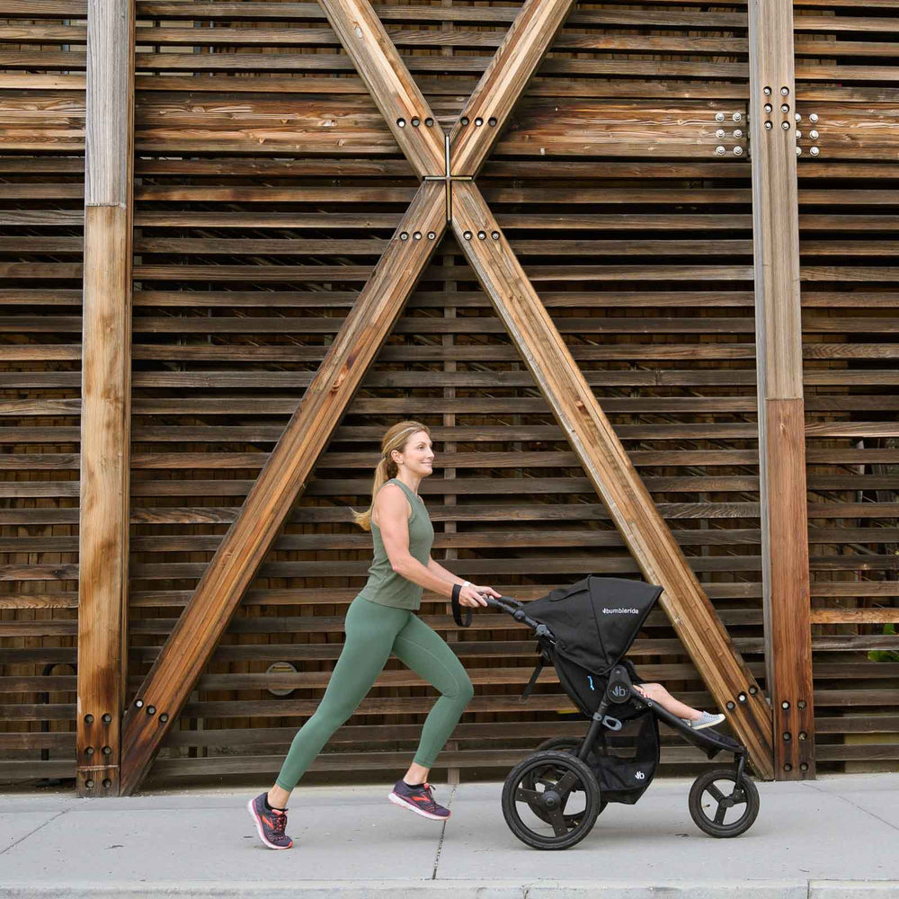 
                      
                        Mother jogging with Bumbleride Australia Speed Jogging Stroller in Black on sidewalk with wood wall in background
                      
                    